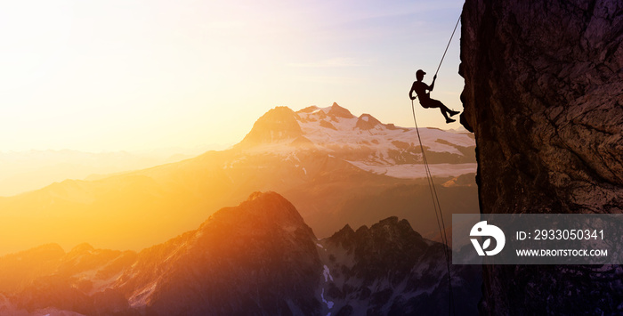 Composite. Silhouette Rappelling from Cliff. Beautiful aerial view of the mountains during a colorful and vibrant sunset or sunrise. Landscape taken in British Columbia, Canada. Concept: Adventure