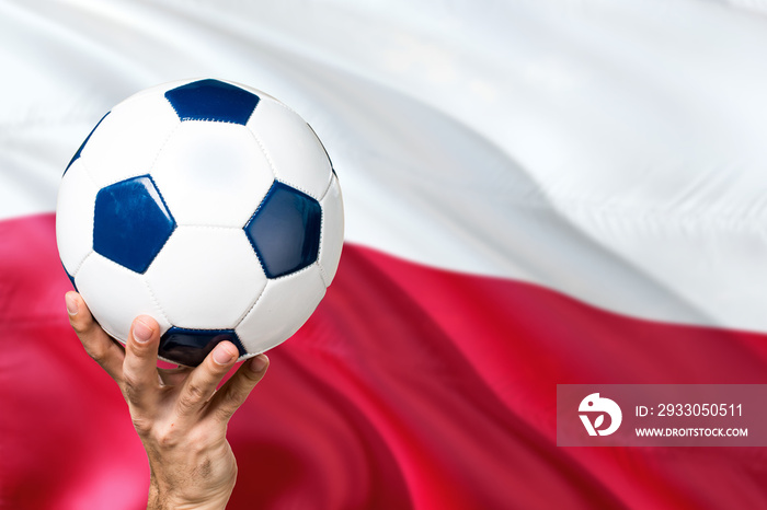 Poland soccer concept. National team player hand holding soccer ball with country flag background. Copy space for text.