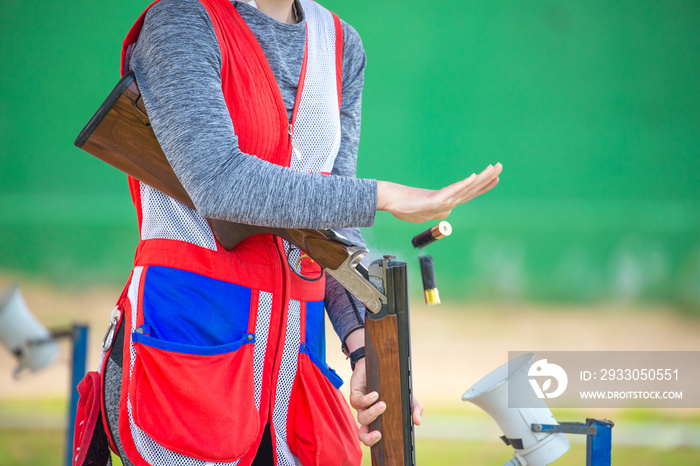 Clay pigeon shooting. An athlete shoots a gun at moving targets isolated on a green background, sport gun shooting, with a place for text, clay pigeon shooting.