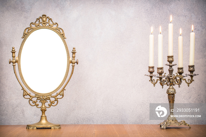 Retro old makeup mirror frame and burning candles in candlestick on wooden table. Vintage instagram style filtered photo