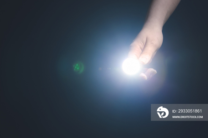 Female hand with modern flashlight on dark background