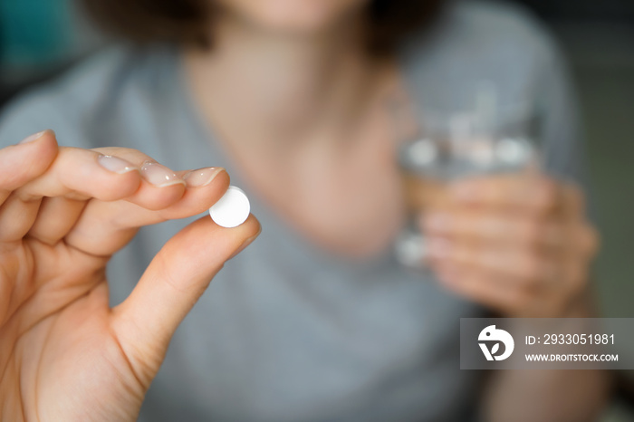 Woman holding pill, closeup