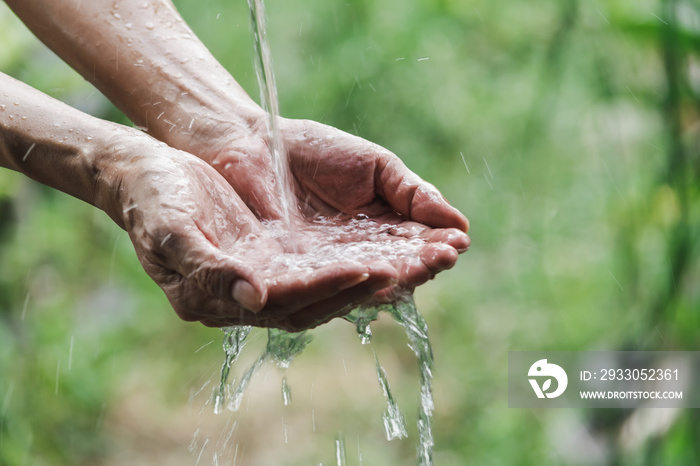 Closeup water flow to hand of women for nature concept on the garden background.