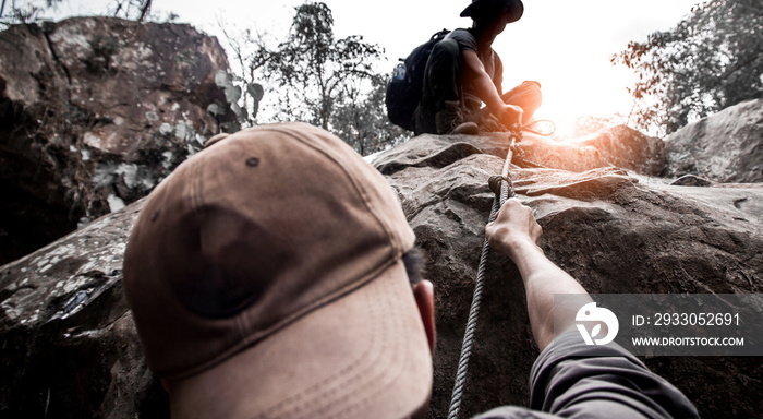 Hiking male help each other in mountains with sunlight.