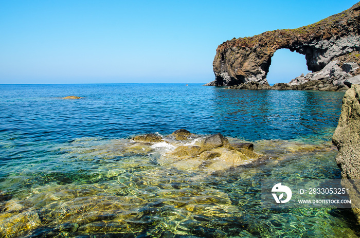 Natural volcanic arch formed from lava on the crystal clear tyrrhenian sea in Punta Perciato, Pollara, Salina. Rocky coastline, Aeolian Islands Archipelago, Sicily, Italy.