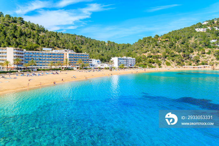 Azure sea water and hotel buildings on beach in Cala San Vicente bay, Ibiza island, Spain