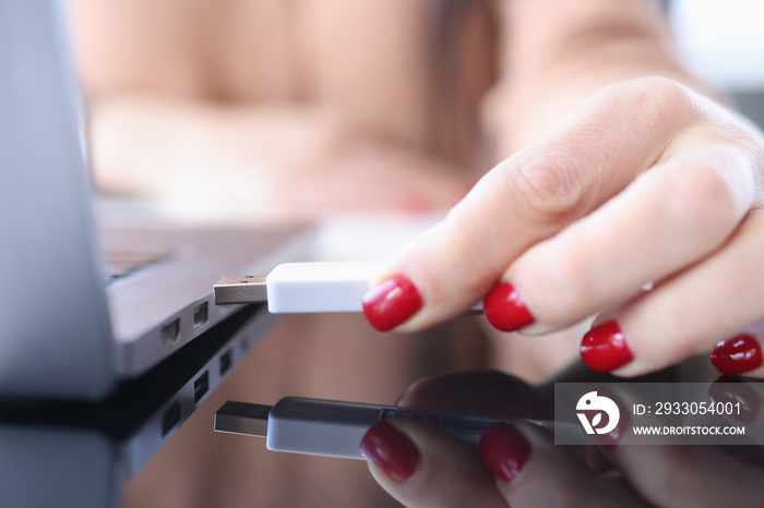 Female hand inserting usb flash into laptop closeup