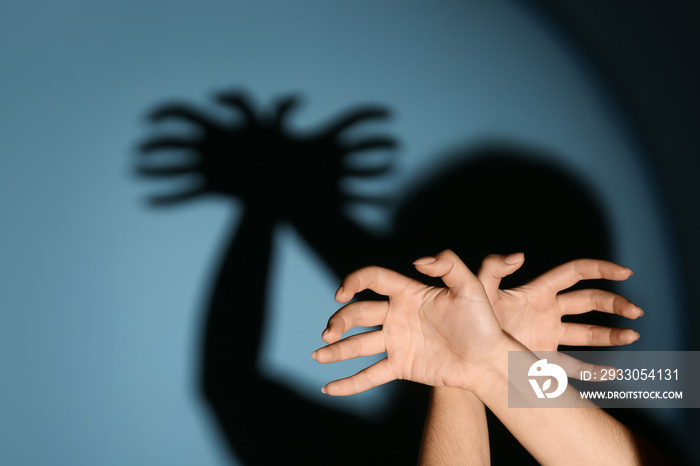 Woman making shadow spider with her hands on color background