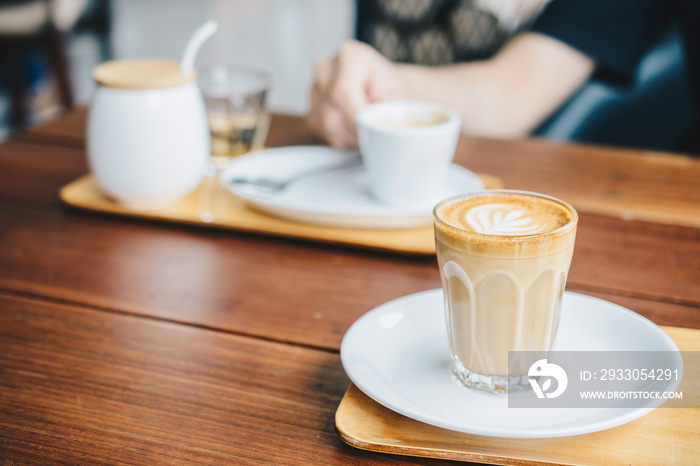 A glass cup of Piccolo latte on wooden table in the coffee shop.