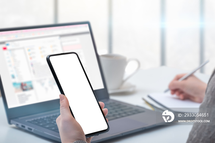 Mockup cellphone. Woman hand holding mobile phone with blank screen in modern office. hand holding smartphone with white screen in office