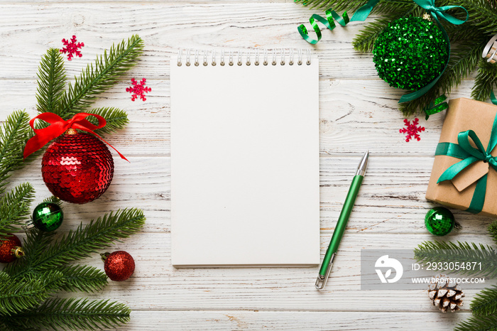 Woman writing Christmas to do list on notebook on colored background with xmas decorations