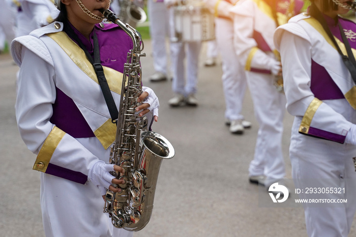 Orchestra students play saxophones in a parade at the school’s athletics event. Soft and selective focus.