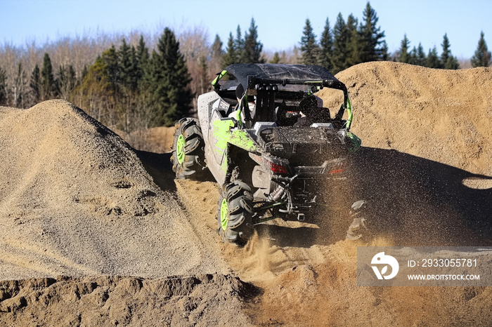 A side-by-side ripping up dirt as it goes up a gravel hill