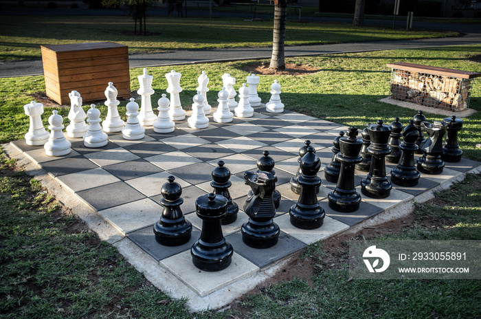 Set of large outdoor chess pieces in correct order to start game in a park