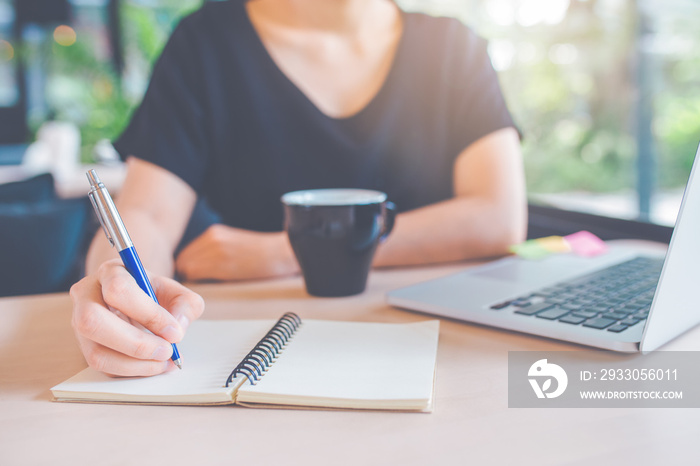 Business woman’s hand is writing on a notebook with a pen.