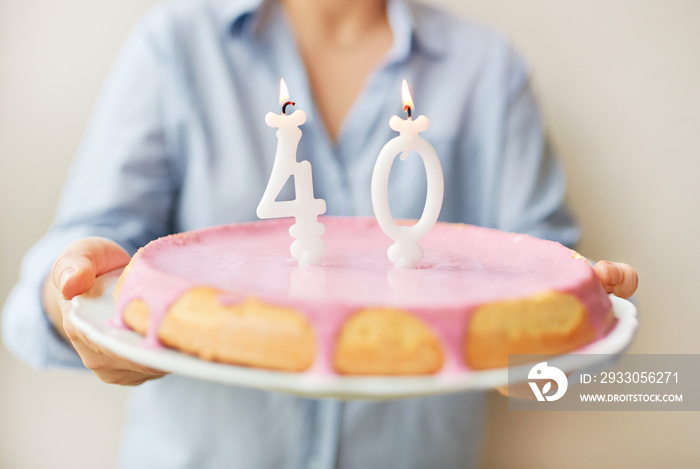 Happy middle age 40 year old woman holding cake with candles