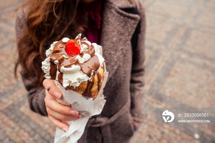 appetite eats a traditional Czech sweet Trdelnik with vanilla cream and strawberries in Prague street