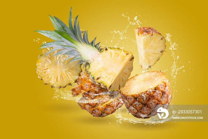 Water Splashing on Split Pineapple Fruit isolated over yellow background.