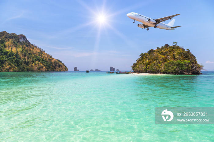 passenger airplane flying over above small island in tropical andaman sea with sunlight. travel destinations concept