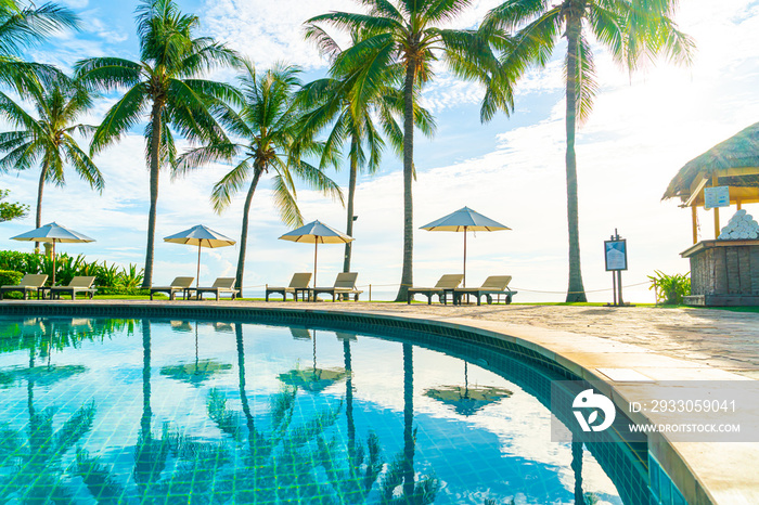 Beautiful luxury umbrella and chair around outdoor swimming pool in hotel and resort with coconut palm tree on sunset  or sunrise sky