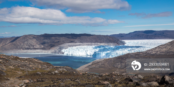 Eqi glacier in white and blue colors with floating icebergs in in blue ocean, Greenland