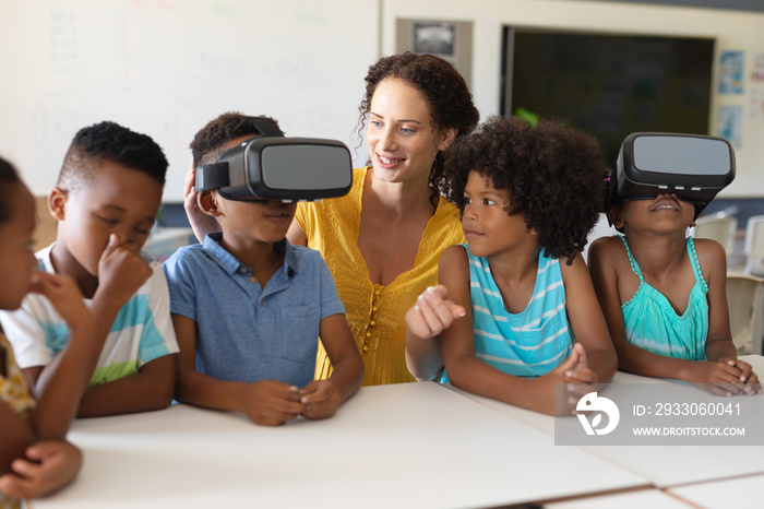 Young female caucasian teacher with african american elementary students wearing vr glasses in class