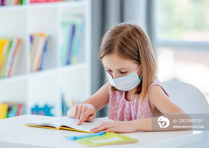 Little girl reading book at classroom