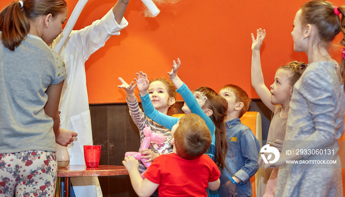 Chemical show for kids. Professor carried out chemical experiments with liquid nitrogen on Birthday little girl.