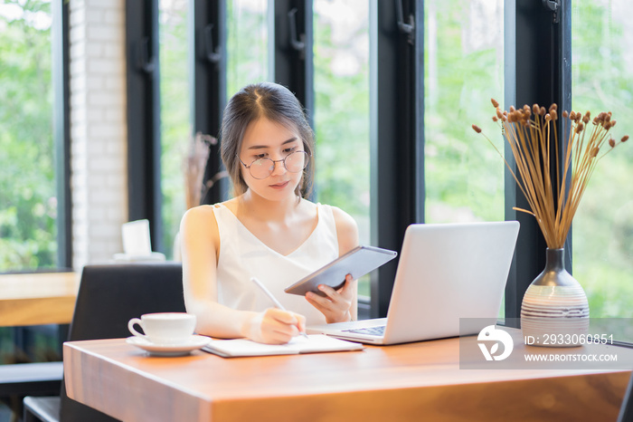 Student hand holding pen and digital tablets writing doing examination in university ,students uniform attending exam classroom educational school: Young business women writes information with laptop