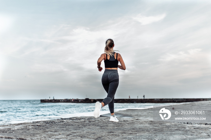 Young fit woman jogging on urban beach