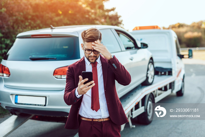 Elegant middle age business man calling towing service for help on the road. Roadside assistance concept.