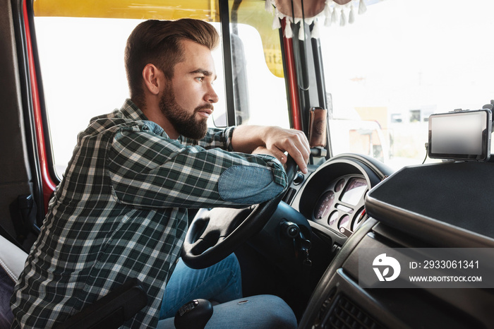 Young professional truck driver sitting inside his vehicle