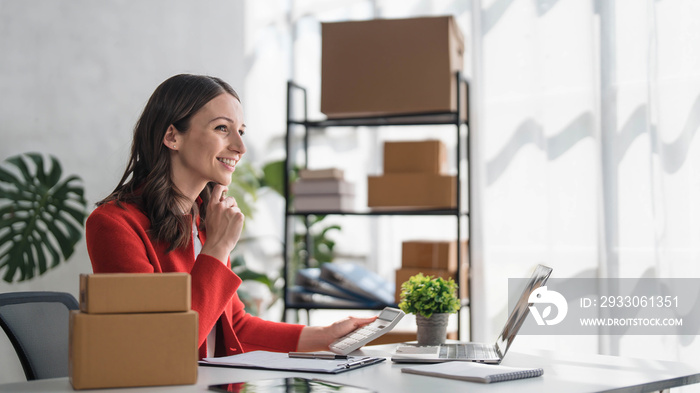 Entrepreneur using calculator with pencil in her hand, calculating financial expense at home office,online market packing box delivery,Startup successful small business owner, SME, concept