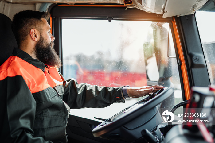 Young garbage removal worker driving a waste truck