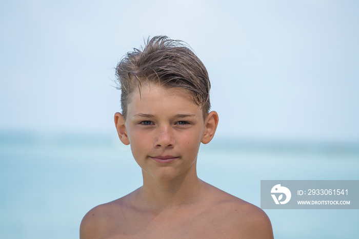 Young boy is enjoying on the beautiful tropical beach at summer, close up portrait