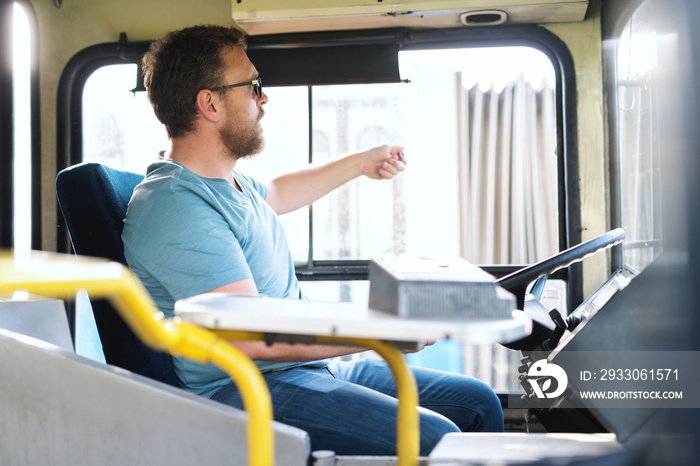 Bus driver sitting on the seat and getting ready to go.