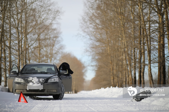 A man near a broken car on a winter day