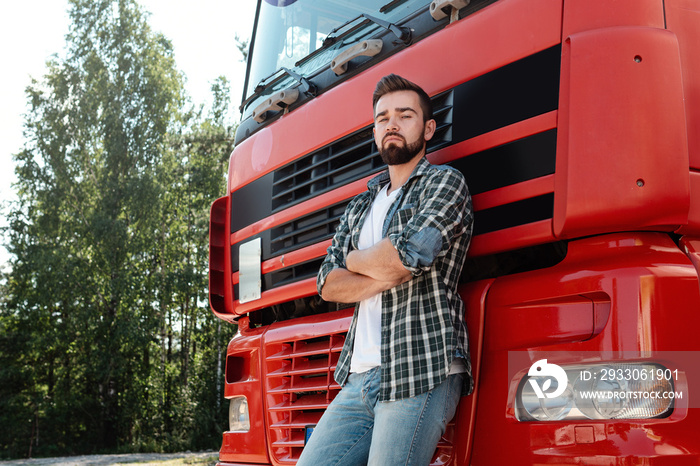 Male truck driver standing beside his red cargo truck