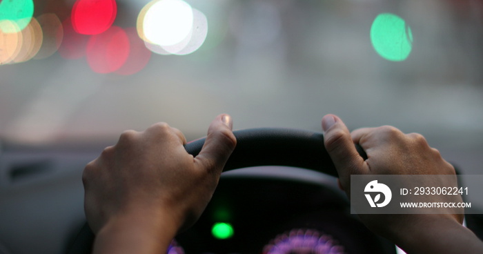 Driver POV hands holding steering wheel waiting. Person hand close-up point of view in red light