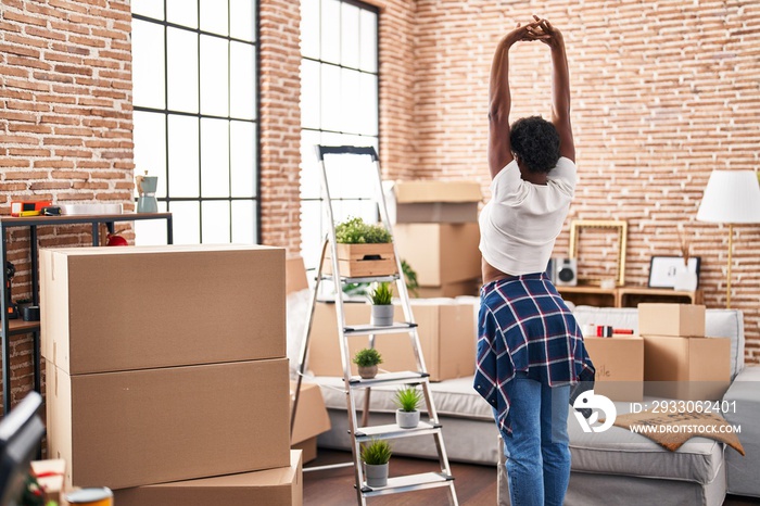 African american woman stretching arms standing on back view at new home