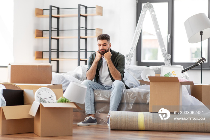 moving, eviction and real estate concept - sad man with boxes at new home