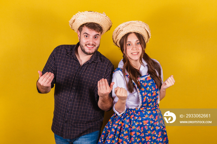 Beautiful couple wearing typical clothes for the Festa Junina. Calling with the hands. inviting.