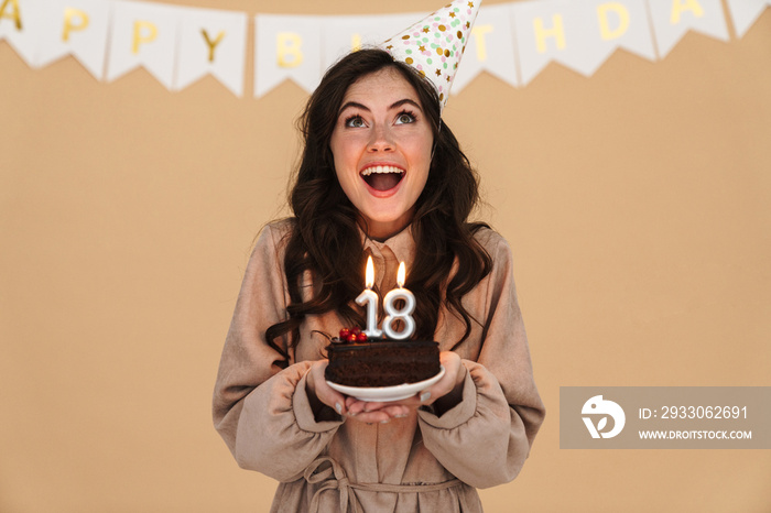 Image of excited young woman smiling while posing with birthday cake