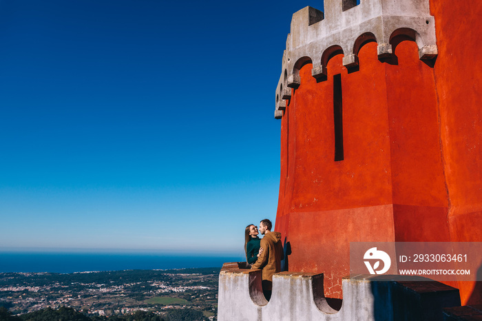 A couple of young happy tourists hugging on the balcony of the Pena Palace in Portugal