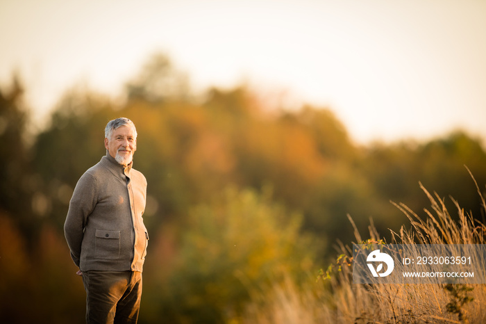 Portrait of handsome senior man in the autumn outdoors. Active senioor enjoying his retirement in the  nature