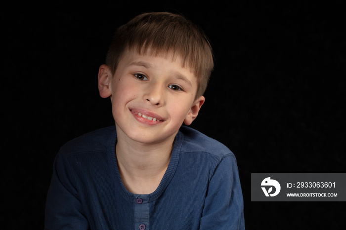 Portrait of a ten-year-old boy on a dark background. The child looks into the camera with intelligent eyes. Handsome boy of school age.