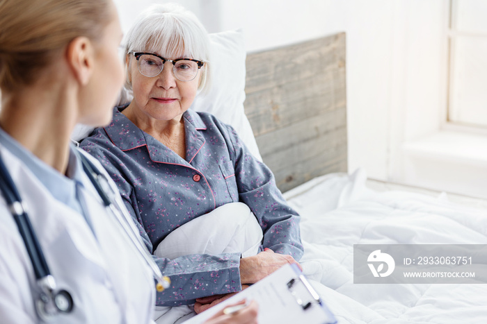 doctor questioning pensioner in hospital