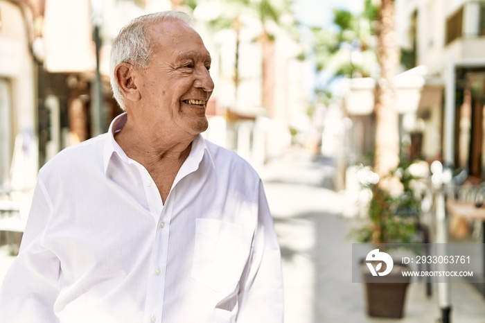 Senior man with grey hair standing happy outdoors on a sunny day. Smiling happy at 70s for retirement.