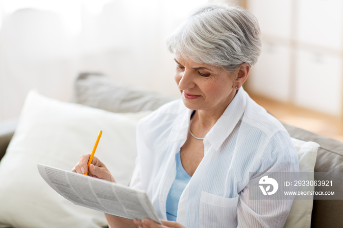 age and people concept - senior woman marking newspaper ad at home