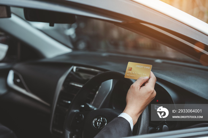 Businessman hands holding credit card in the car instead of cash.